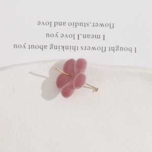 Boucles d'oreilles fleurs roses floquées avec cœur doré sur un plateau blanc