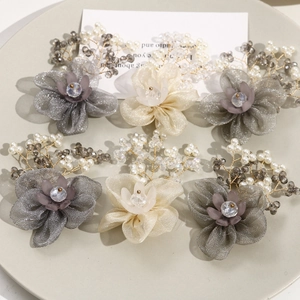Detailed view of handcrafted mesh flower hairpins with pearls and beads on a ceramic tray