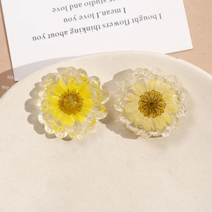 Dettaglio dei ciondoli in resina con margherite gialle essiccate per gioielli fatti a mano