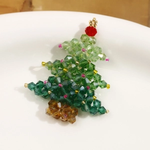 Macro shot of handmade beaded green crystal Christmas tree pendant on white porcelain