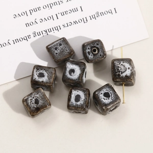 Macro detail of cube-shaped ceramic beads with black and white spotted reactive glaze finish