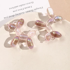 Detailed view of two iridescent acrylic balloon dog charms on a beige textured tray