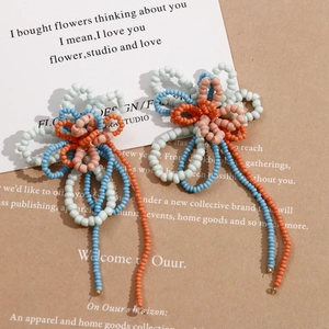Close-up of handmade beaded flower earrings with colorful tassels on a vintage background