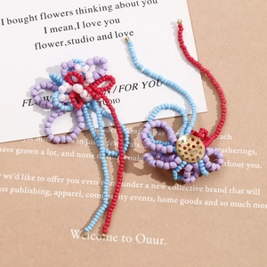 Macro detail of handmade beaded flower charms with long colorful tassels and gold accents