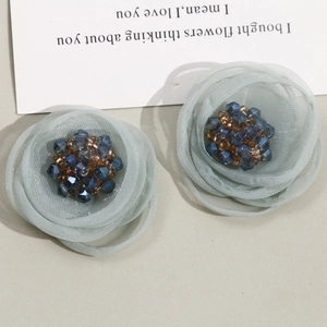Macro detail of mesh flower hair accessories with shimmering bead centers and blue petals