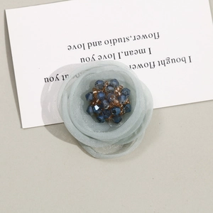 Detail view of handmade light blue mesh flower hair accessory with crystal bead core