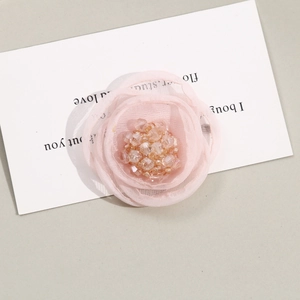 Macro detail of a handmade pink mesh flower accessory with sparkling crystal center beads