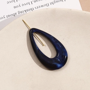 Detailed macro view of dark blue marble texture resin teardrop hair clip with golden metal pin
