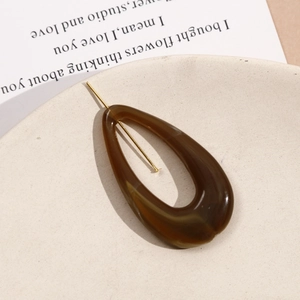 Detail view of water-drop shape amber resin earring parts in a decorative ceramic bowl