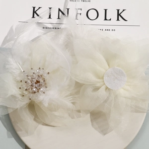 Elegant white mesh flower earrings with soft feathers and crystal beads on a tray