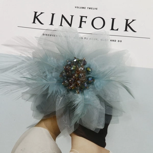 Detail of a handmade floral hair clip with light blue mesh, soft feathers and crystal beads