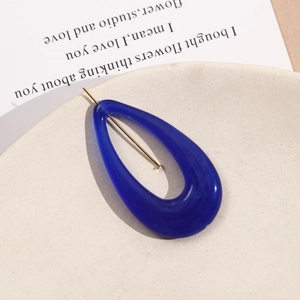 Close-up of royal blue teardrop resin earrings with gold studs on a matte tray