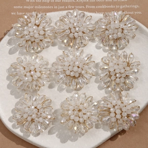 Detailed view of handmade crystal flower beads arranged in a matrix on a ceramic plate