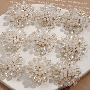 Macro shot of handmade beaded crystal flower earrings on a white marble display tray