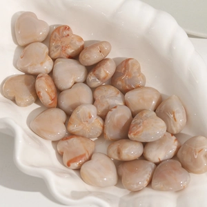 Polished heart-shaped DIY resin beads with marble texture in a ceramic dish