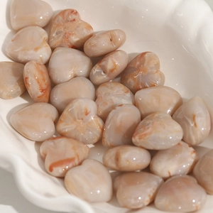 Detailed macro of 20mm heart-shaped DIY resin beads with marble texture in a ceramic tray
