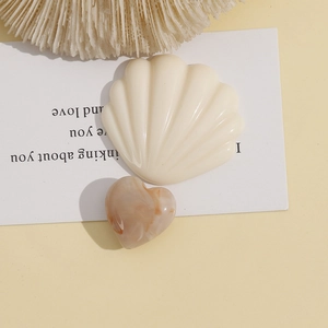 Close-up of 20mm marbled resin heart and cream shell pendants for DIY jewelry making