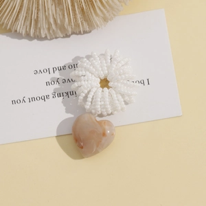Macro view of cream amber marble heart pendant on white beaded elastic hair tie