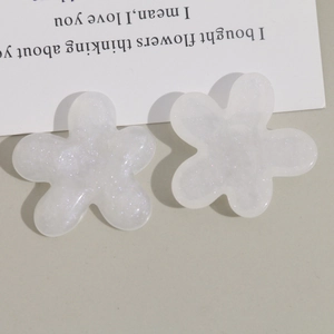 Détail de breloques fleurs en résine pailletée semi-transparente pour bijoux et coiffures