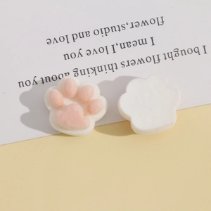Close-up of plush resin cat paw DIY charms with pink pads on a gift card background