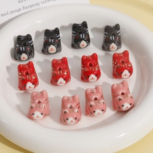Detailweergave van handgeschilderde keramische kattenkralen in zwart, rood en roze voor DIY