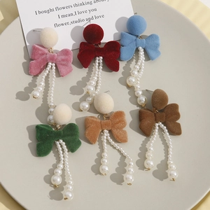 Detail of six-color velvet bow earrings with long imitation pearl tassels in a dish