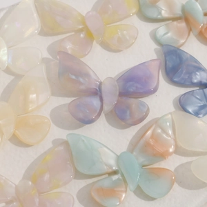 Close-up of DIY acetate butterfly charms with gradient cream pastel colors and marble texture