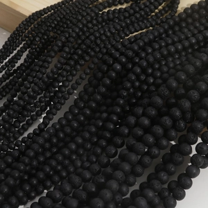 Macro view of porous black lava stone beads with natural texture on wooden background