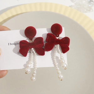 Detail of burgundy velvet bow earrings with white imitation pearl tassels on a card