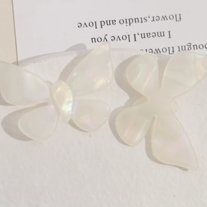 Macro detail of iridescent butterfly hair accessories in a creamy translucent white finish