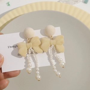 Detail of cream flocked bow earrings with elegant faux pearl tassel on display