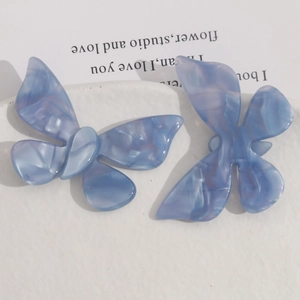 Macro detail of blue marble texture acetate butterfly hair accessories on white tray