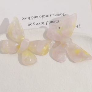 Detailed macro view of two cream gradient butterfly charms made of acetic acid on a plate