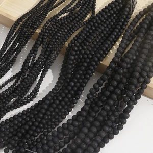 Macro shot of natural black lava stone beads showing porous texture in multiple sizes