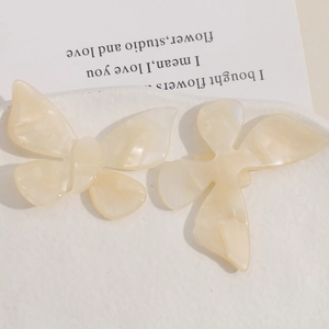 Detailed macro view of cream butterfly acetate hair accessories on a ceramic plate