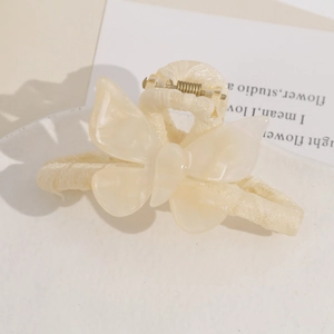 Macro shot of cream butterfly hair claw with pearlescent finish and fabric-wrapped handle