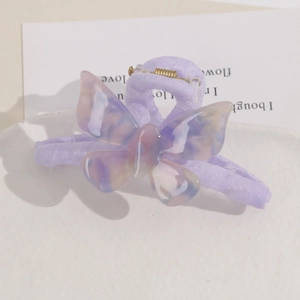 Close-up of purple gradient acetate butterfly hair clip with marble texture on cream base