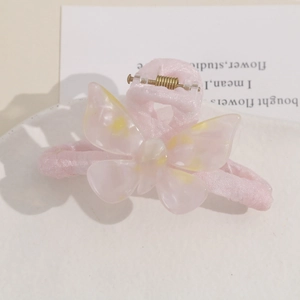 Close-up of pink plush hair claw clip with a translucent resin butterfly and yellow spots