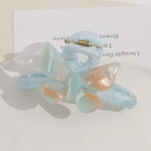 Detail of a blue and orange gradient butterfly hair claw clip on a textured tray