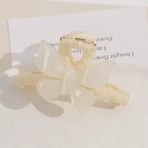 Detailed close-up of pearlescent butterfly acetate charm on a cream-colored fabric hair clip
