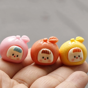 Detailed macro view of miniature 3D fruit resin charms with cute smiling baby faces