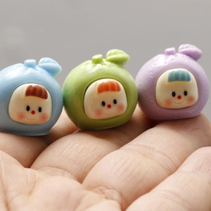 Macro view of three resin cartoon fruit charms in blue, green and purple colors for DIY