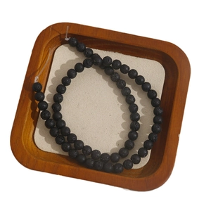 Natural black lava stone beads on a wooden tray for DIY jewelry necklaces and bracelets