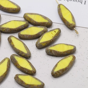 Macro view of vintage style spindle glass beads with yellow and brown textured patterns
