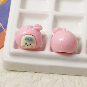 Detailed macro view of pink resin fruit baby charms with realistic citrus peel texture