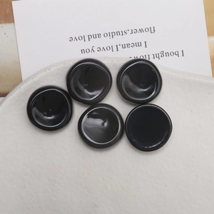 Primer plano de dijes redondos de resina negra de 22mm en una bandeja de cerámica blanca