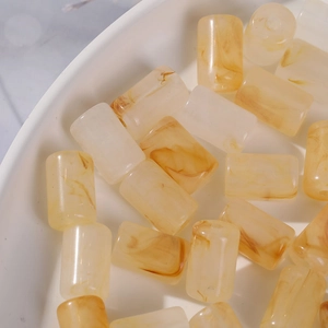Detailed macro view of amber marble pattern acrylic cylinder beads for DIY jewelry making