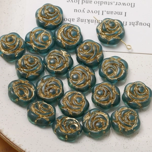Macro detail of blue rose glass beads with gold-rimmed petals for DIY jewelry making