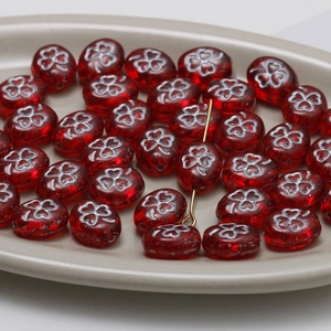 Macro shot of red oval Czech glass beads with clover patterns for DIY jewelry making