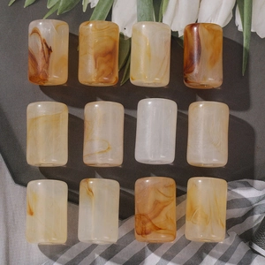 Macro detail of 12 amber-tone resin barrel beads with marble texture for jewelry DIY